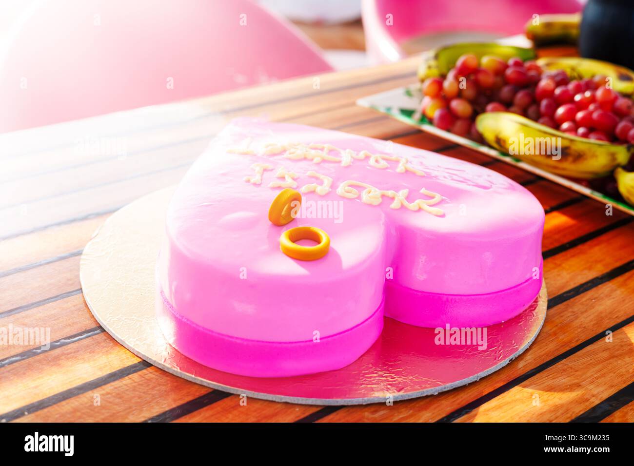 Rosafarbener Kuchen in Herzform mit Ringen. Stockfoto