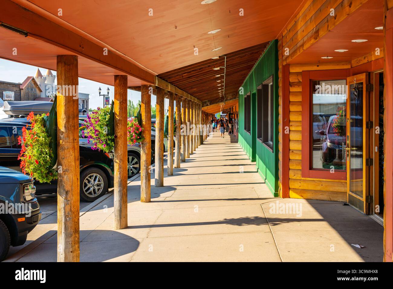 Blumenkörbe säumen den überdachten Gehweg vorbei an alten West-Themen-Läden, Cafés und Drogerien in der kleinen Touristenstadt Wall, South Dakota. Stockfoto