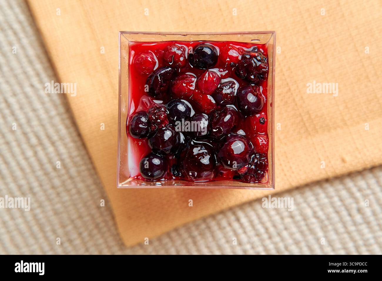 Eine köstliche Tasse gemischter Beeren, glasiert in süßem Sirup, perfekt zum Nachtisch oder Snack, ideal für Sommerspezialitäten und erfrischende Genüsse Stockfoto