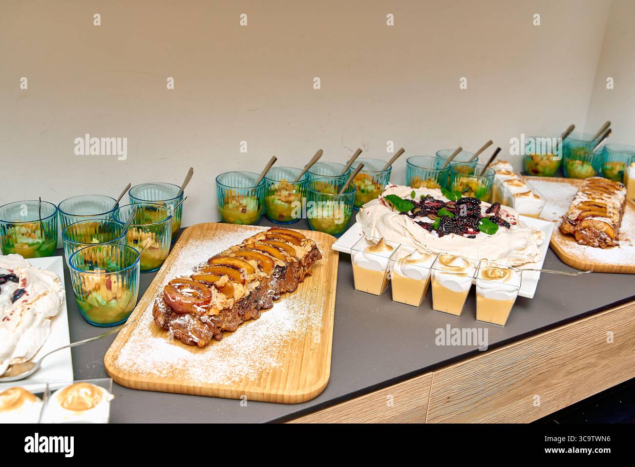 Köstliche Auswahl an Desserts mit Pavlova, Obstkuchen und cremigen Pudding auf einem modernen Serviertisch, perfekt für jede Feier oder Versammlung Stockfoto