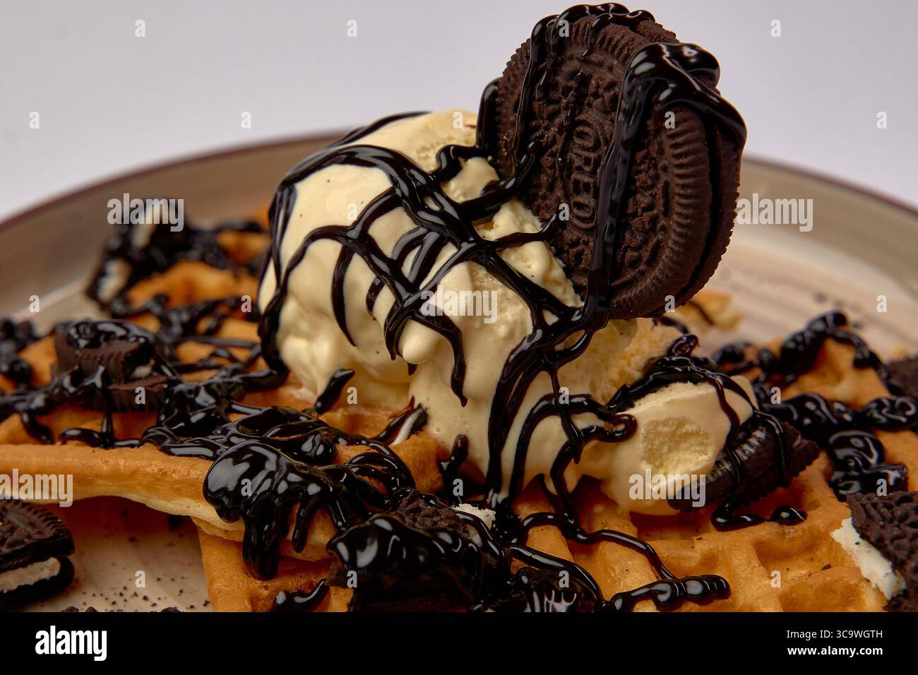Köstliches Waffeldessert mit cremigem Eis, reichhaltiger Schokoladensauce und knusprigen Oreo-Keksen für ein himmlisches Erlebnis Stockfoto