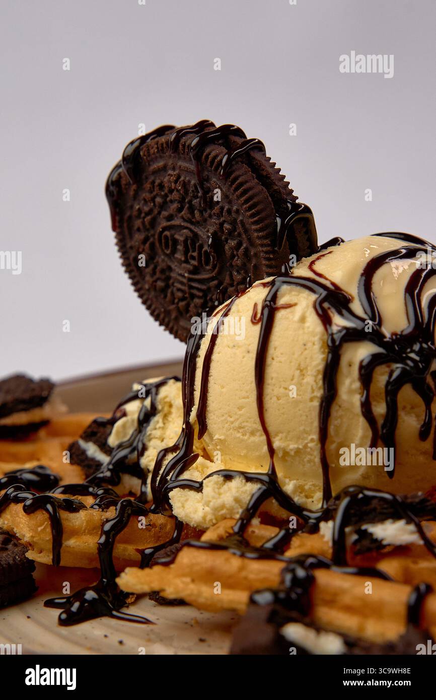 Dekadente Nachspeise: Eine verführerische Waffel mit cremigem Eis, Oreos und reichhaltiger Schokoladensauce für ein süßes Erlebnis Stockfoto