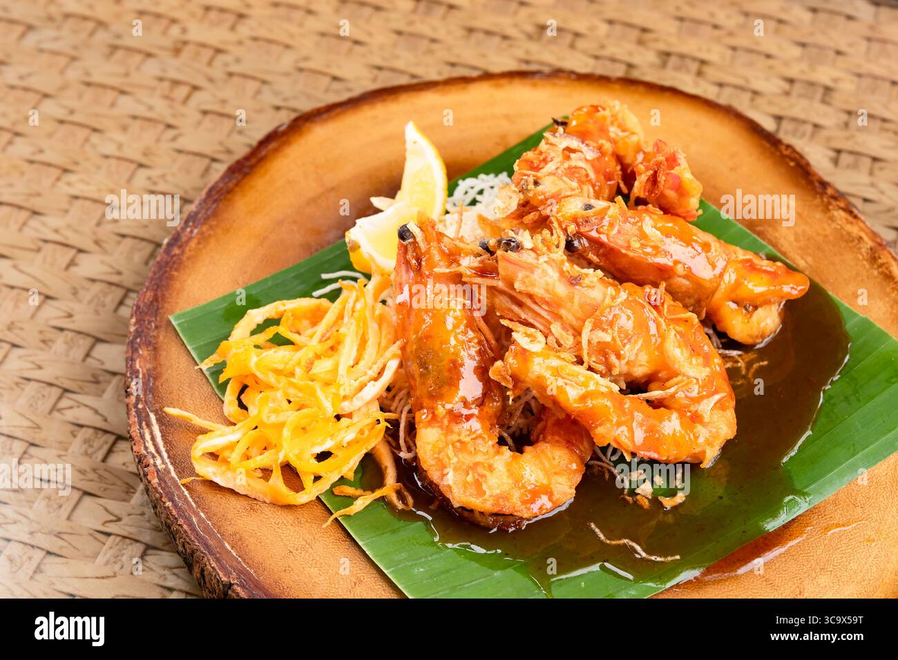 Frittierte Garnelen mit Tamarindensauce auf Bananenblatt und Holzteller mit Ei, gebratenen Nudeln und Limette. Stockfoto