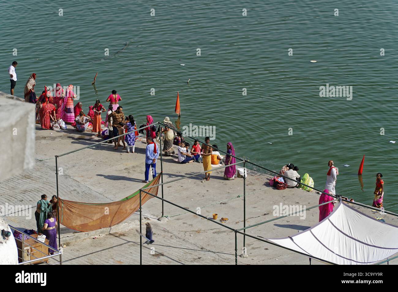 Menschen treffen sich am traditionellen Uferufer zu religiösen Aktivitäten, umgeben von Flaggen in Indien, Pushkar Mela, Puschkar, Großkamel und Viehmarkt Stockfoto
