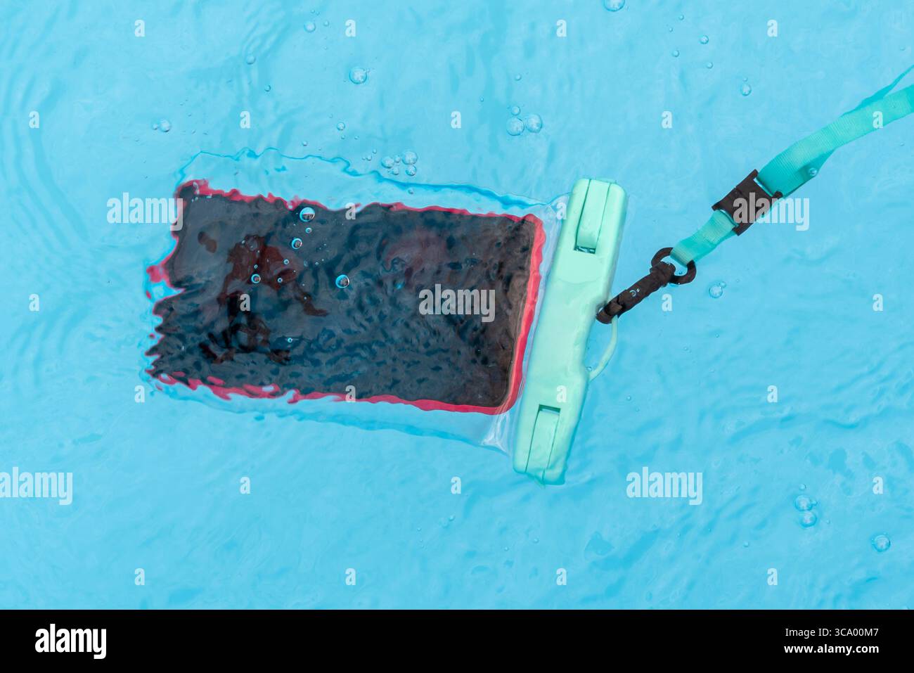 Wasserdichte Handytasche, die in einem türkisfarbenen Swimmingpool schwimmt, gewährleistet Schutz und Zugänglichkeit Stockfoto