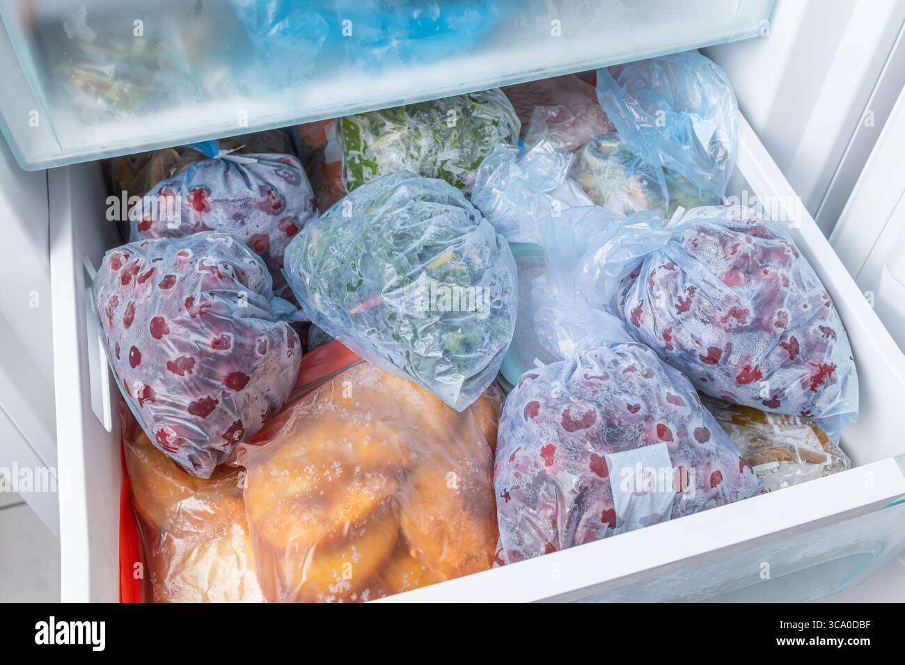 Gefrorenes Obst und Gemüse in Kunststoffbeuteln im Gefrierschrank mit frostfreiem Haushaltskonzept Stockfoto