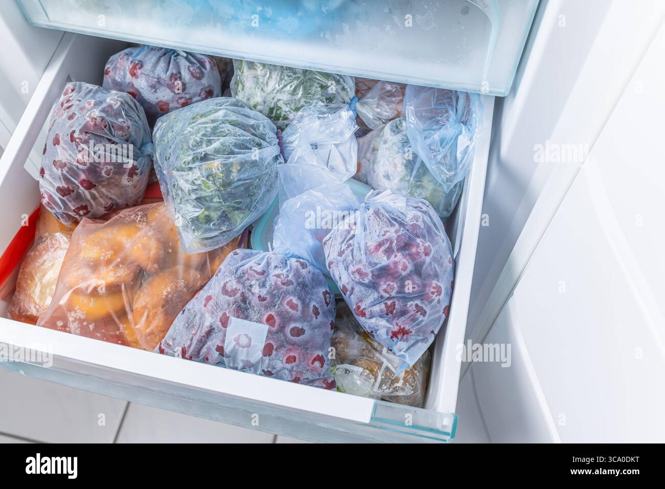 Gefrorenes Obst und Gemüse in Kunststoffbeuteln im Gefrierschrank mit frostfreiem Haushaltskonzept Stockfoto