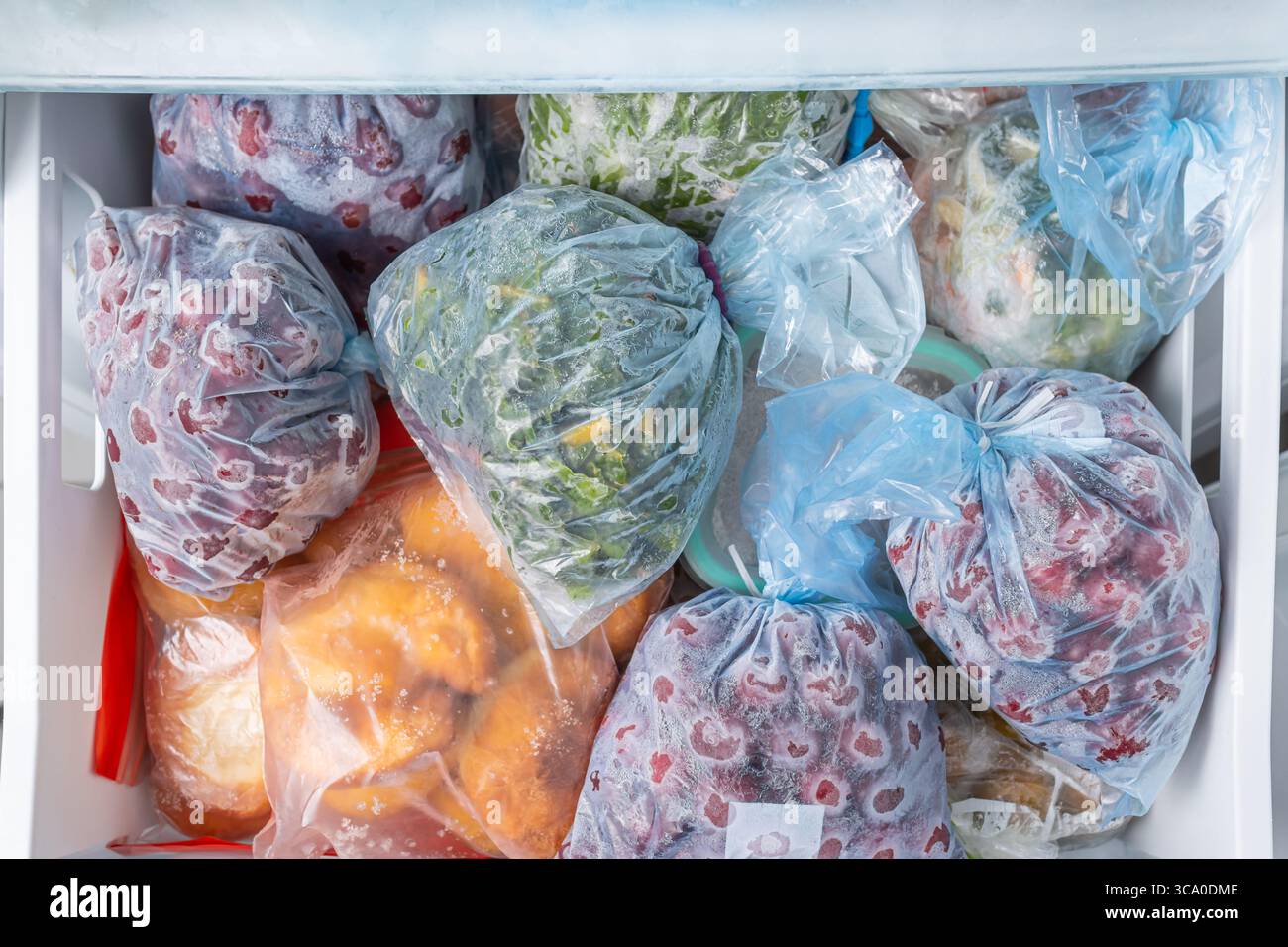 Gefrorenes Obst und Gemüse in Kunststoffbeuteln im Gefrierschrank mit frostfreiem Haushaltskonzept Stockfoto