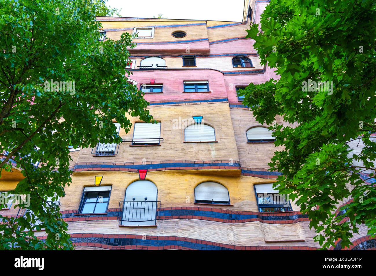 Farbenfrohe und einzigartige Fassade des Wohnkomplexes Waldspirale inmitten üppiger Bäume in Darmstadt mit innovativem architektonischem Design. Stockfoto