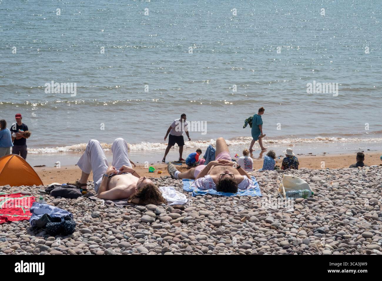 Sidmouth, 6. August 25 Menschen genießen den Strand von Sidmouth Devon, wenn die Temperaturen bis Mitte der 20er Jahre wieder steigen. Die Sidmouth Folk Week hat Tausende von Besuchern in die Stadt gebracht und ein Nachmittag am Strand hat sich als beliebt erwiesen. Das Met Office sagt ein Wochenende vor dem fabelhaften Wetter voraus. Photo Central/Alamy Live News Stockfoto
