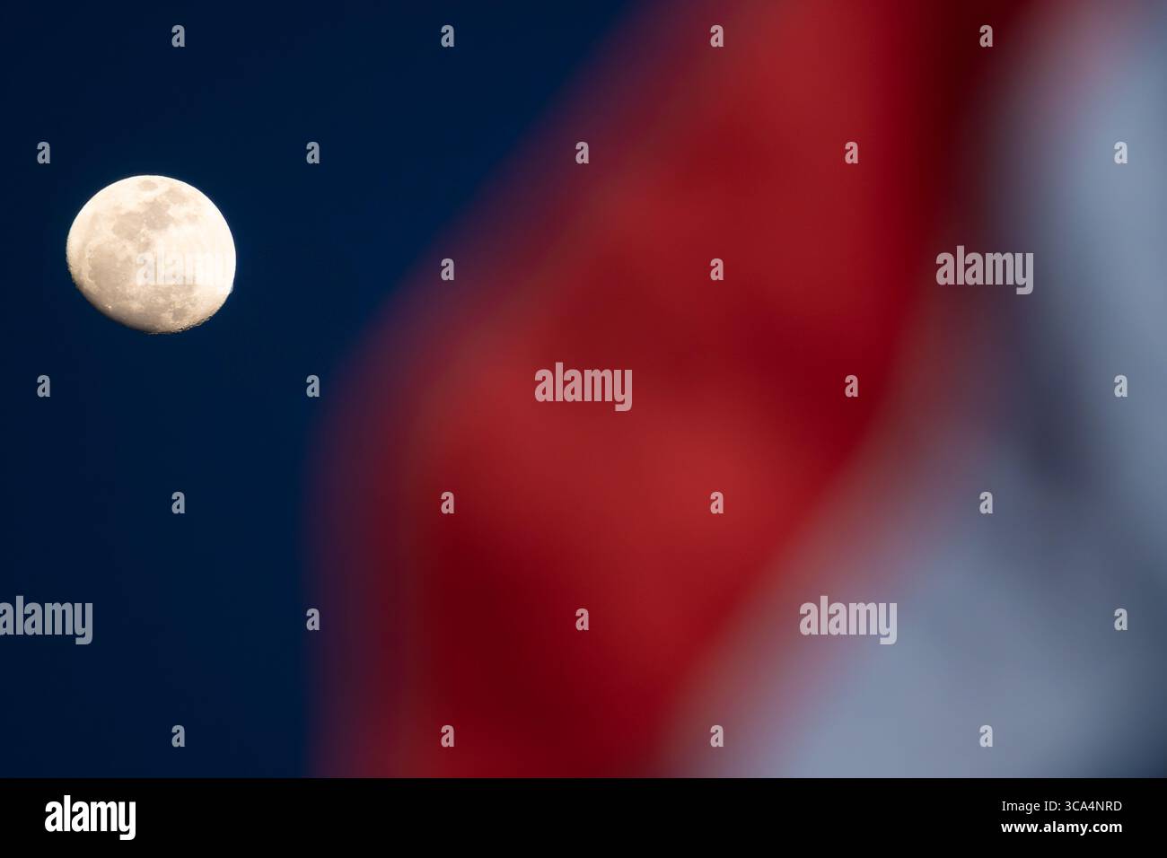 Ein Mond, der am Abendhimmel leuchtet, mit der winkenden Flagge der Republik Indonesien im Vordergrund, der als Monat der Unabhängigkeit markiert Stockfoto