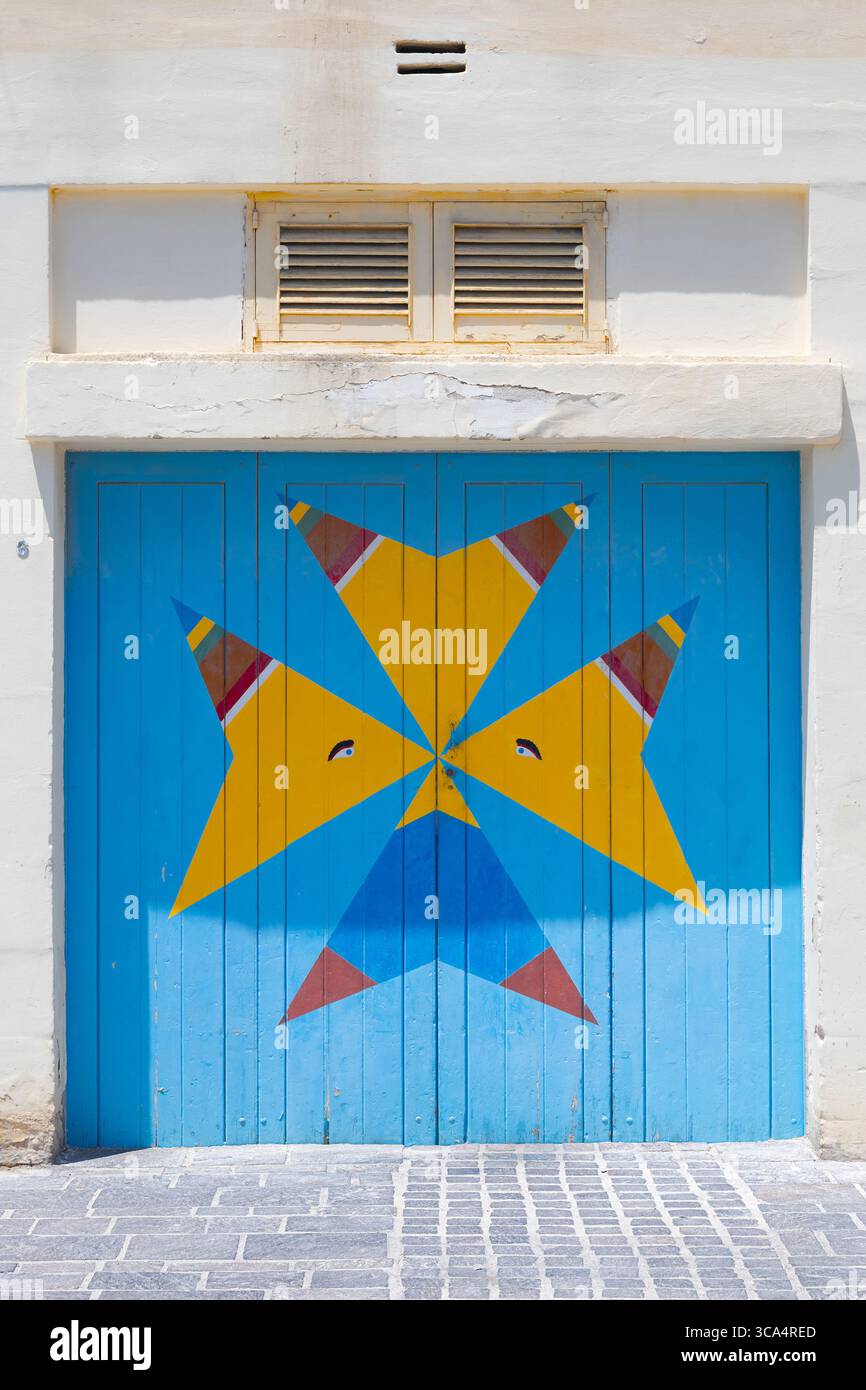 Ein Garagentor in Marsaxlokk, Malta. Blaue Tür im Stil des Maltesischen Kreuzes. Auch das Auge des Horus oder das Auge des Osiris. Stockfoto