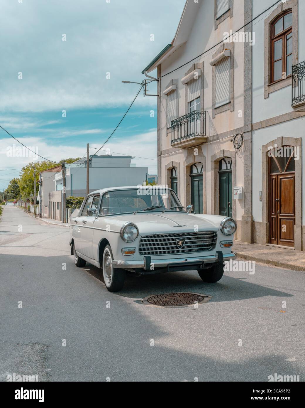 Klassisches Weißes Oldtimer-Peugeot An Der Traditionellen Portugiesischen Village Street, Historische Steinarchitektur. Retro-Automobil, nostalgisch, ländliches Portugal Stockfoto