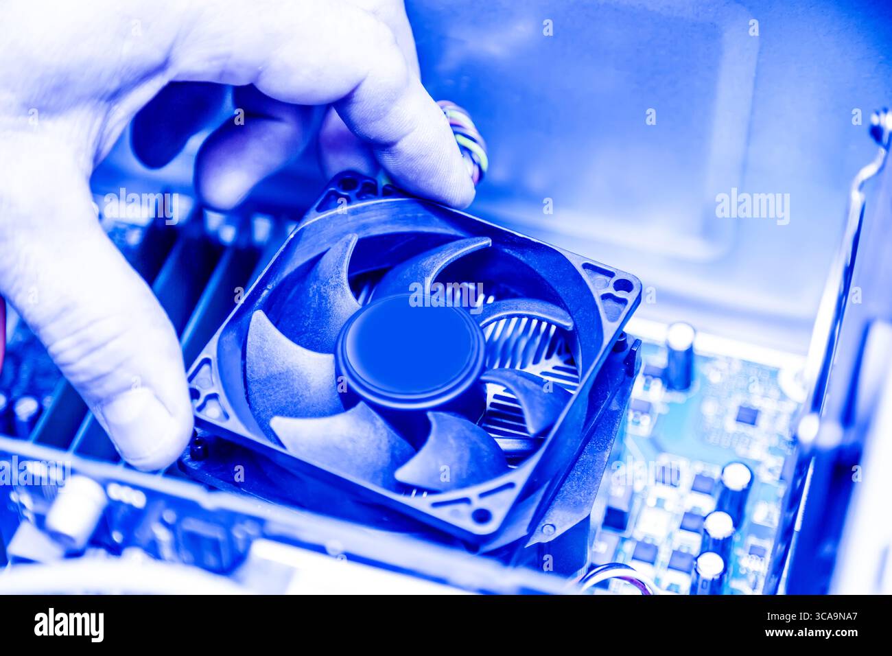 Der Techniker händigt die Installation des CPU-Kühlerlüfters auf einer pc-Hauptplatine aus. Getöntes Bild. Stockfoto