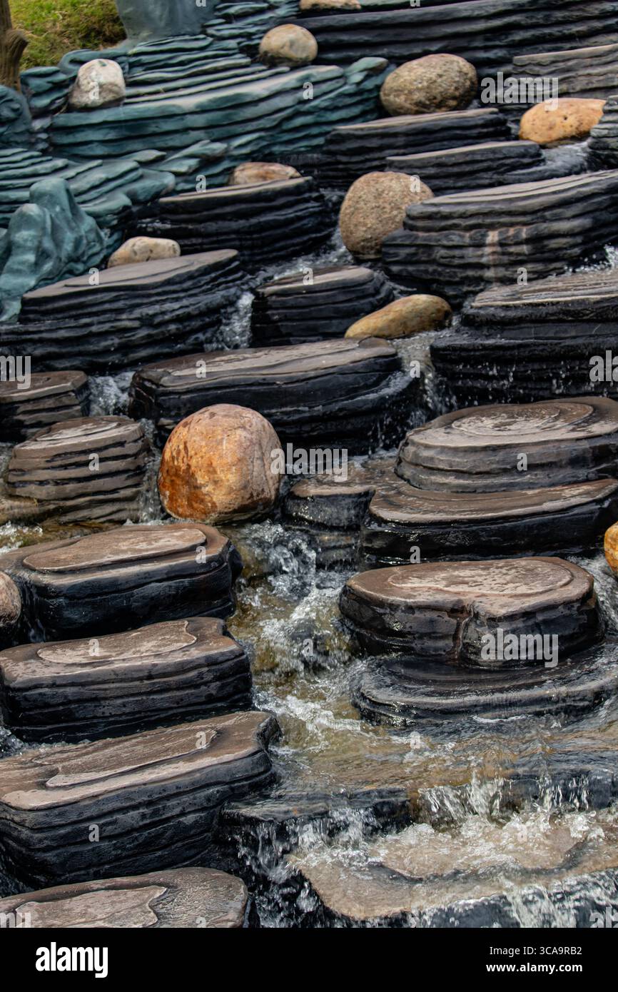 Malerischer künstlicher Wasserfall mit Felsstrukturen im Park Stockfoto