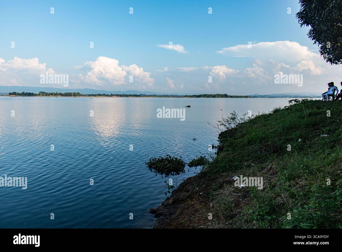Stille See mit bewölktem Himmel und Dschungelhügeln Stockfoto