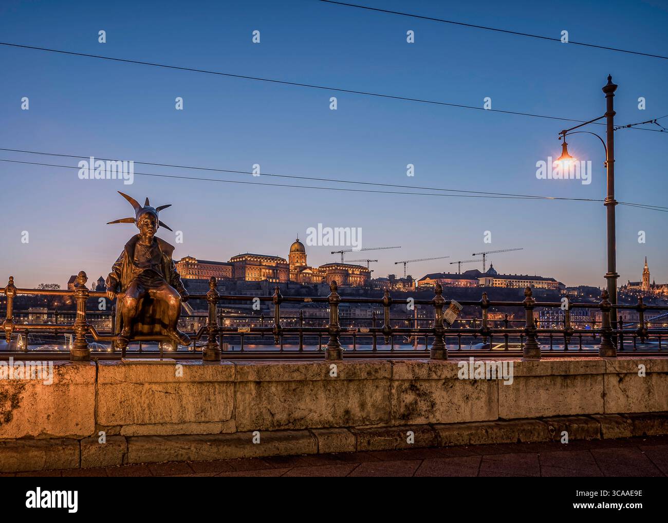 Statue der kleinen Prinzessin von László Martonon an der Donaupromenade in der Abenddämmerung, mit beleuchtetem Schloss Buda im Hintergrund, Ungarn, März 2025 Stockfoto