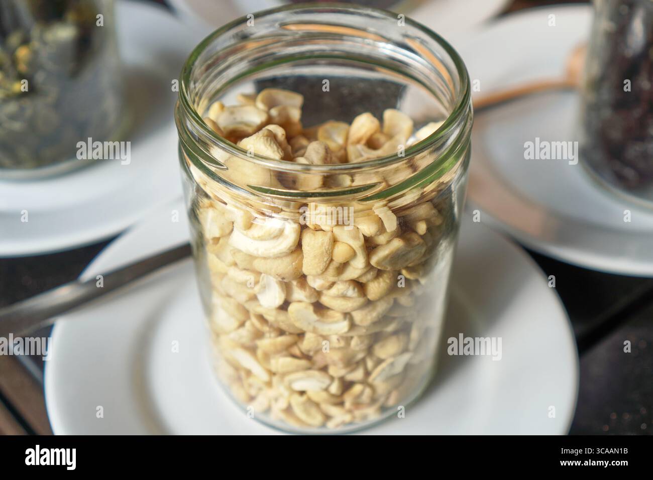 Gesunde Nüsse, serviert in einem transparenten Glasglas als Frühstücksbelag. Stockfoto