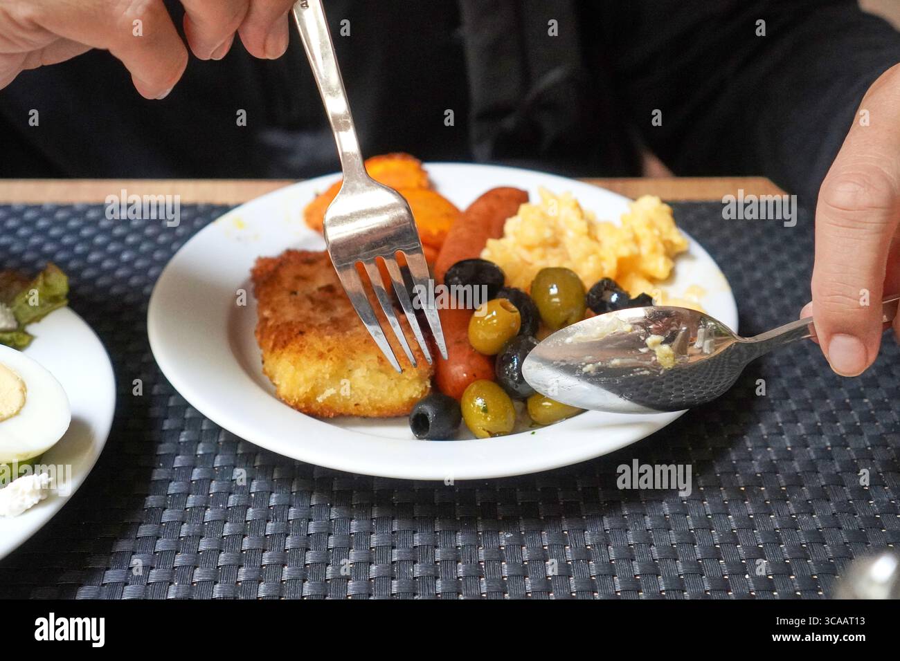 Herzhaftes Frühstück mit Rührei, gegrillter Wurst und Garnitur auf einem weißen Teller. Stockfoto