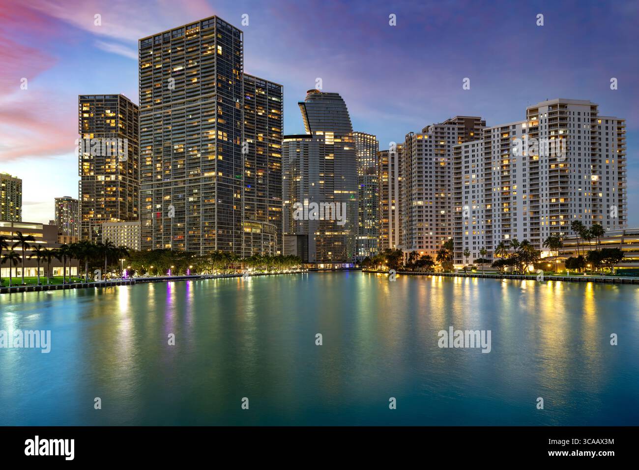 Miamis Viertel Brickell: Eine pulsierende urbane Landschaft, in der elegante Wolkenkratzer die Uferpromenade säumen und unter einem bunten Himmel leuchten. Stockfoto