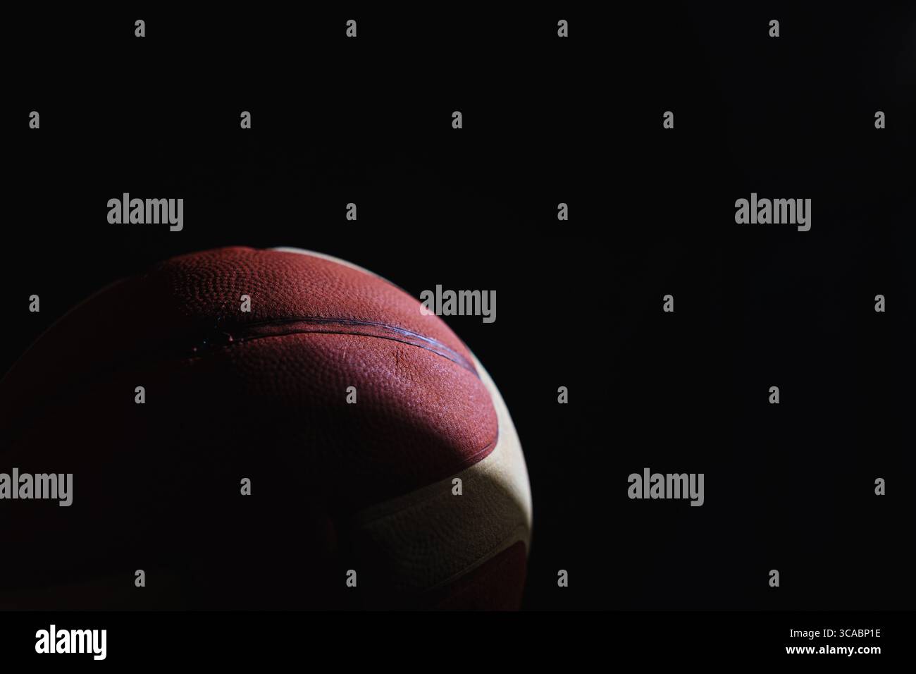 Nahaufnahme eines roten Basketballs mit weißen Streifen auf schwarzem Hintergrund Stockfoto
