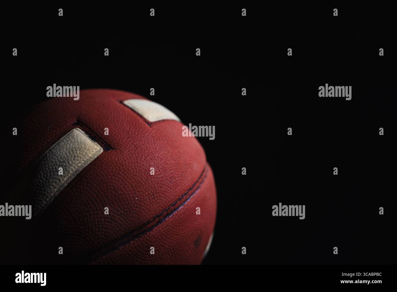 Nahaufnahme eines roten Basketballs mit weißen Streifen auf schwarzem Hintergrund Stockfoto