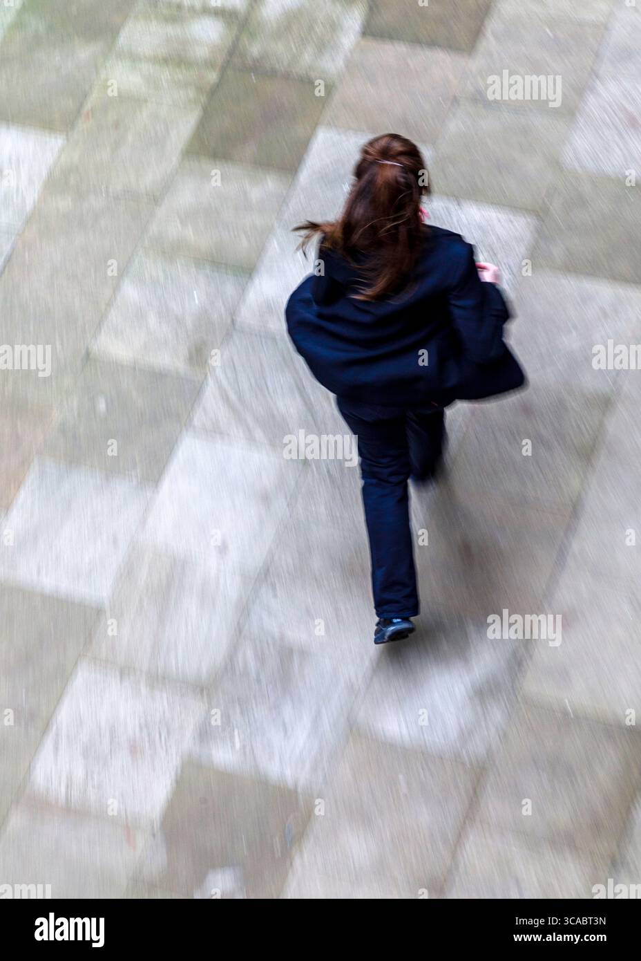 Eine Person in einem dunklen Anzug läuft auf einer Steinoberfläche. Stockfoto