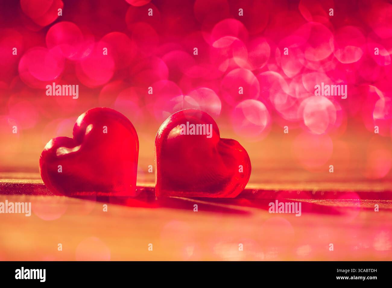 Rote kleine dekorative Herzen auf hölzernem Hintergrund. Liebes- oder romantisches Valentinstag-Konzept. Getönt Stockfoto