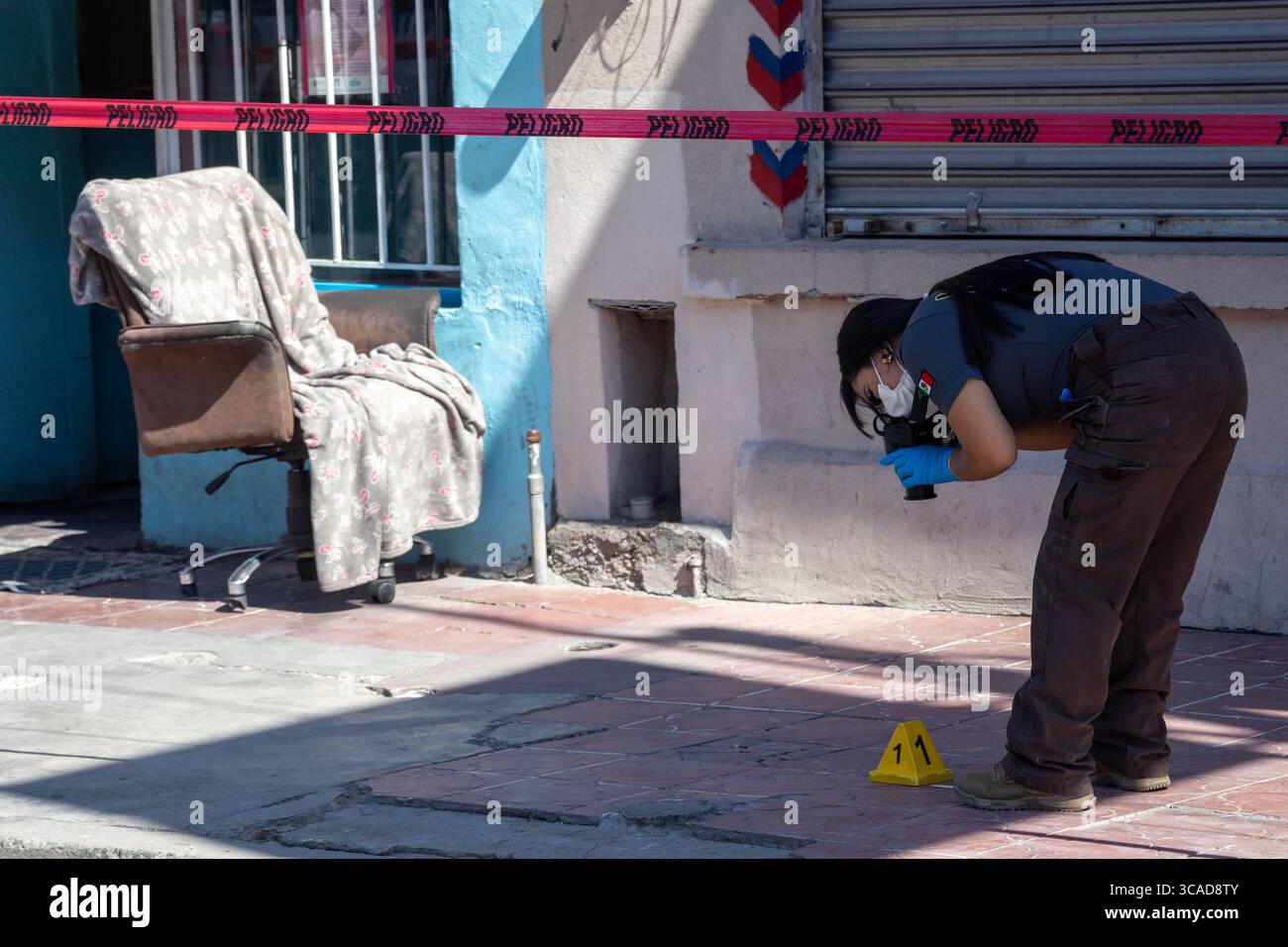 Ein forensischer Ermittler untersucht Beweise an einem Tatort, der mit rosa Klebeband markiert ist, in Ciudad Juarez, einer Stadt, die von städtischer Gewalt betroffen ist. Stockfoto