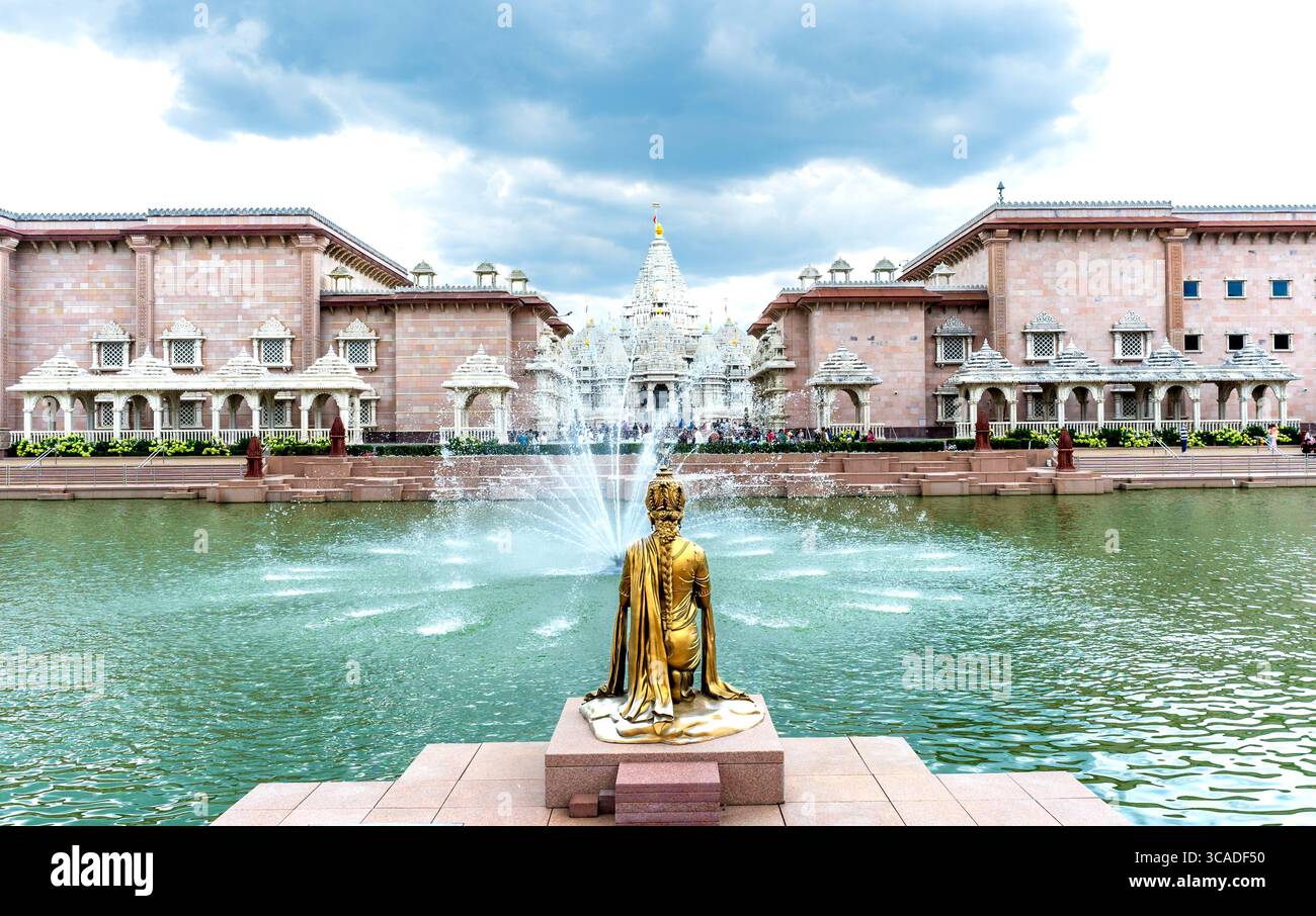 Robbinsville, NJ - USA - 2. August 2025 Ein ruhiger Pool mit einer goldenen knienden Statue und tanzenden Springbrunnen schmückt die Vorderseite des BAPS Swaminarayan Akshardham Stockfoto