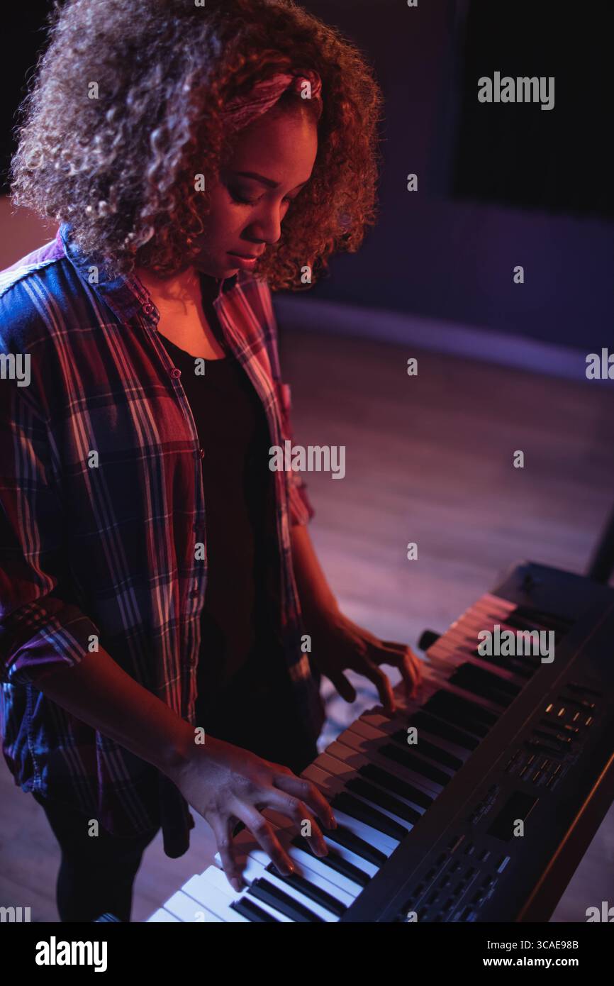 Bühnenleuchten, die warme und kühle Töne auf die elektronische Tastatur auf Holzboden mit dunklen Paneelen geben Stockfoto