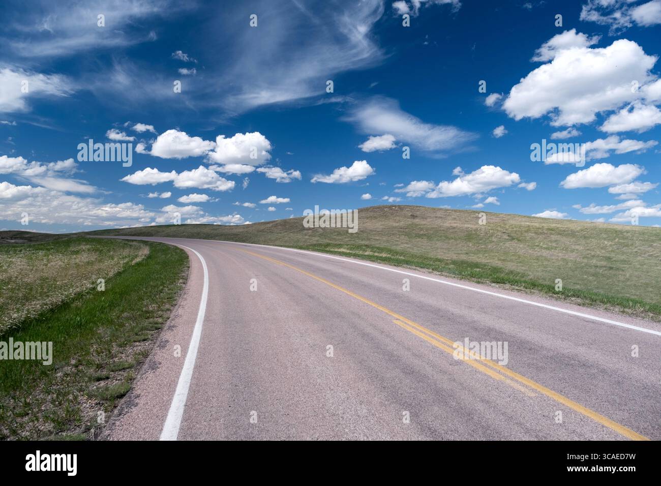 Malerischer Abschnitt der kurvenreichen Autobahn unter blauem Himmel mit Wolken in der Prärie der Hochebene von South Dakota Stockfoto