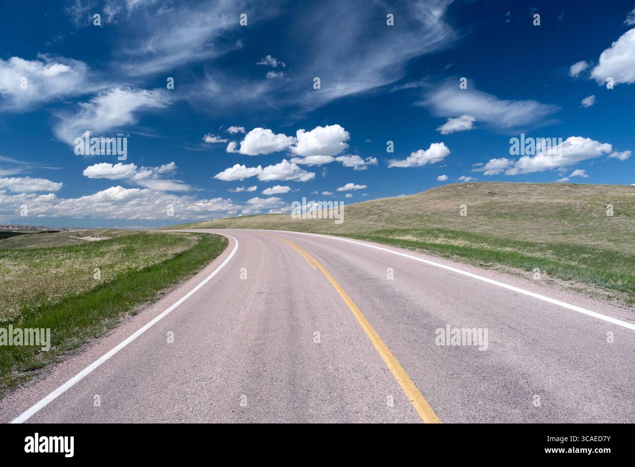 Malerischer Abschnitt der kurvenreichen Autobahn unter blauem Himmel mit Wolken in der Prärie der Hochebene von South Dakota Stockfoto