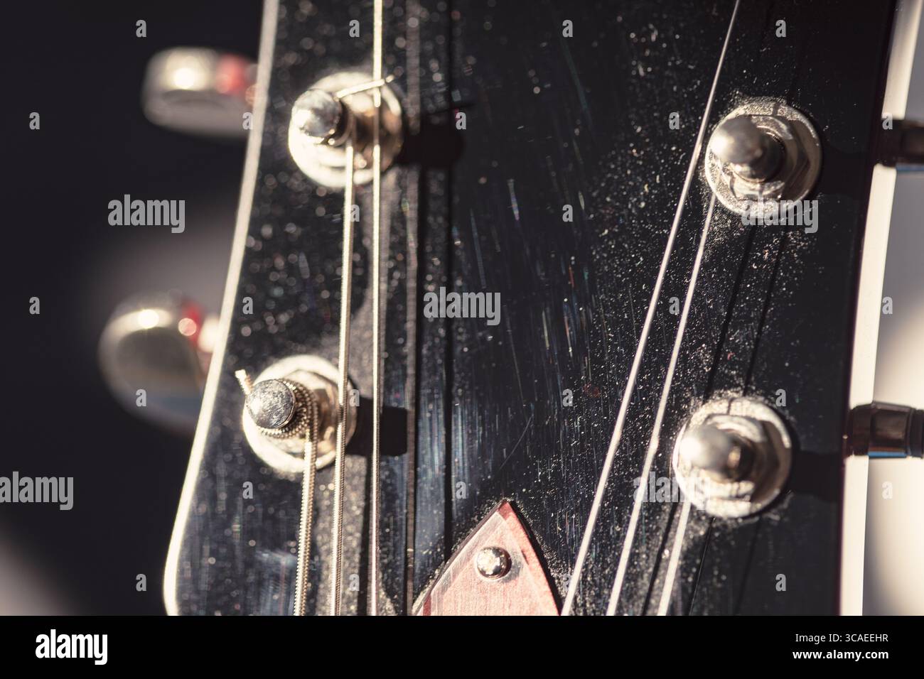 Gitarrenkopfstock mit komplexen Stimmknöpfen und Streichern. Strukturierte Oberfläche und präzise Details unterstreichen handwerkliches Können und musikalischen Charakter Stockfoto