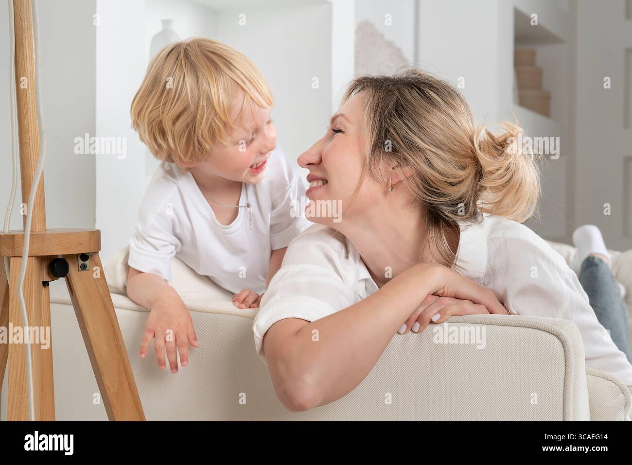 Eine glückliche Kindheit, Mutter und Sohn auf der Couch, entspannen mit einem Kind, Familienabend, Kommunikation mit einem Kind, familiäre Gefühle Stockfoto