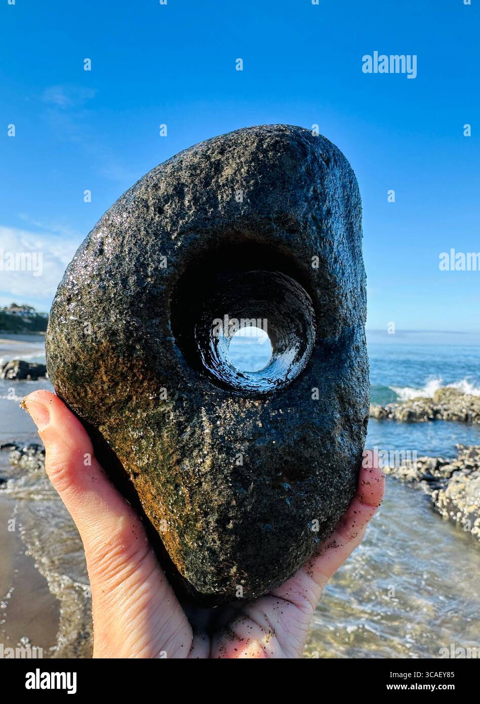 Nahaufnahme einer Hand, die einen Stein hält, an einem Strand in Lincoln City, Oregon. - Smartphone-aufgenommenes Stockfoto