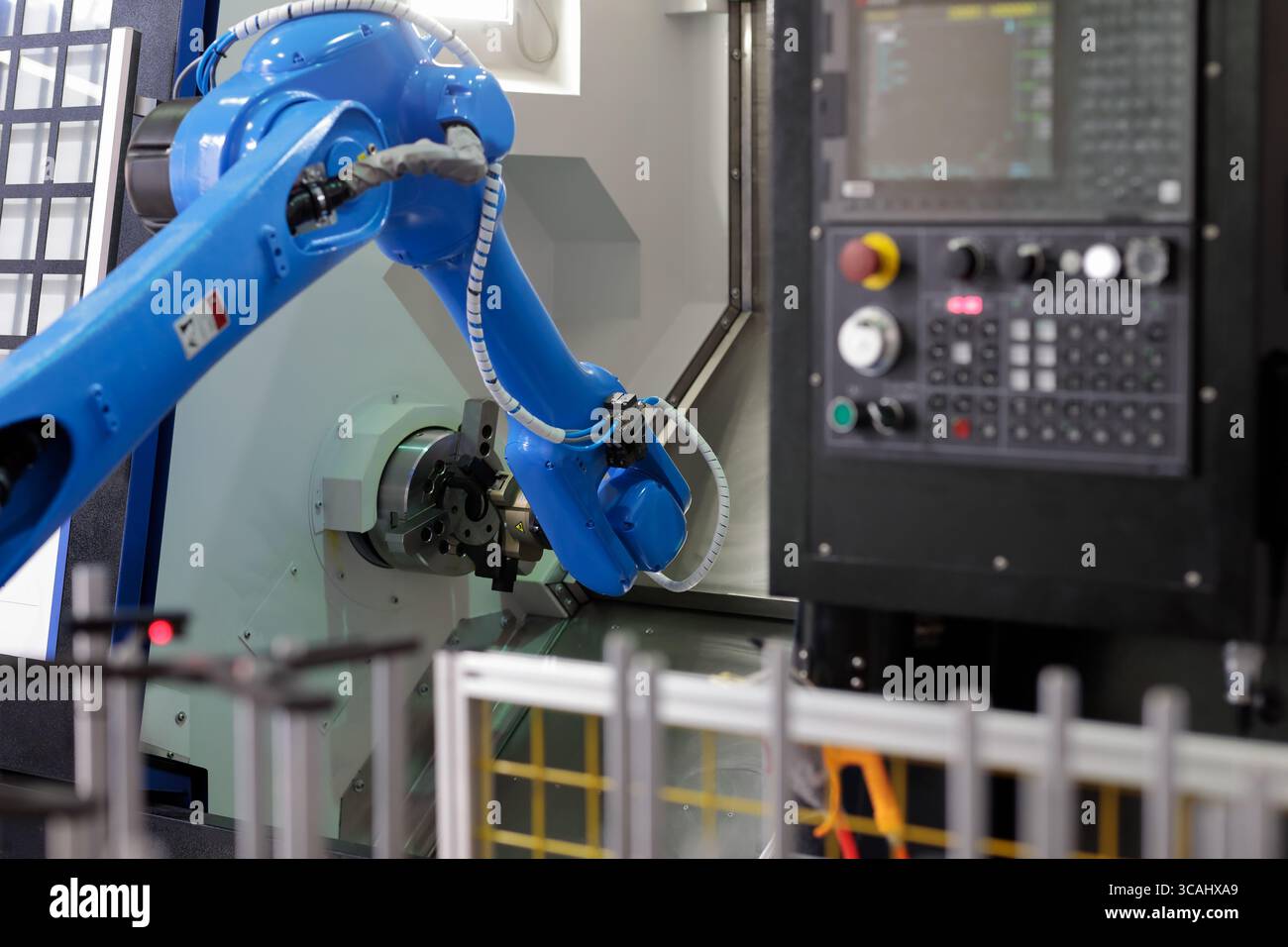 Roboter, der Teile in die CNC-Drehmaschine lädt. Automatisiertes Laden von Teilen in CNC-Drehmaschinen mit Roboterarm. Selektiver Fokus. Stockfoto