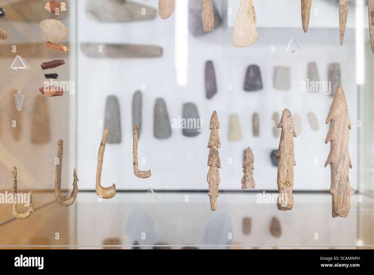Museum mit antiken Artefakten, darunter Angelhaken, Pfeilspitzen und Steinwerkzeugen. Die Ausstellung zeigt prähistorische Handwerkskunst und Stockfoto