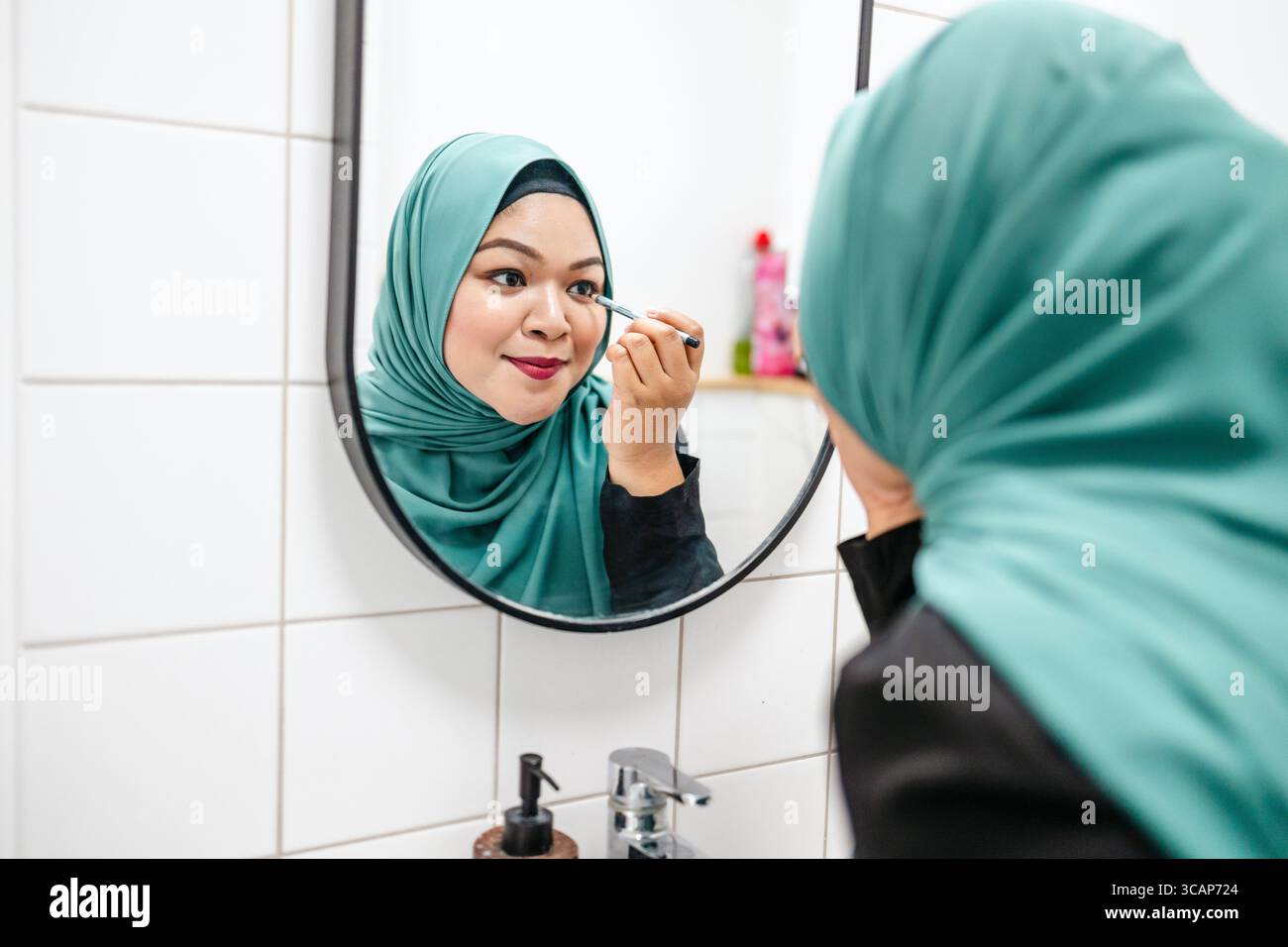 Frau im Hijab, die Augen im Badezimmer zu Hause schminkt Stockfoto