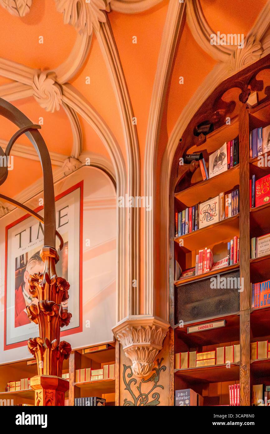 Neogotische Säulen und geschnitzte hölzerne Bücherregale im historischen Lello Buchladen Porto Portugal. Dekorative, literarische, orangefarbene Decke, Buchauslagen Stockfoto
