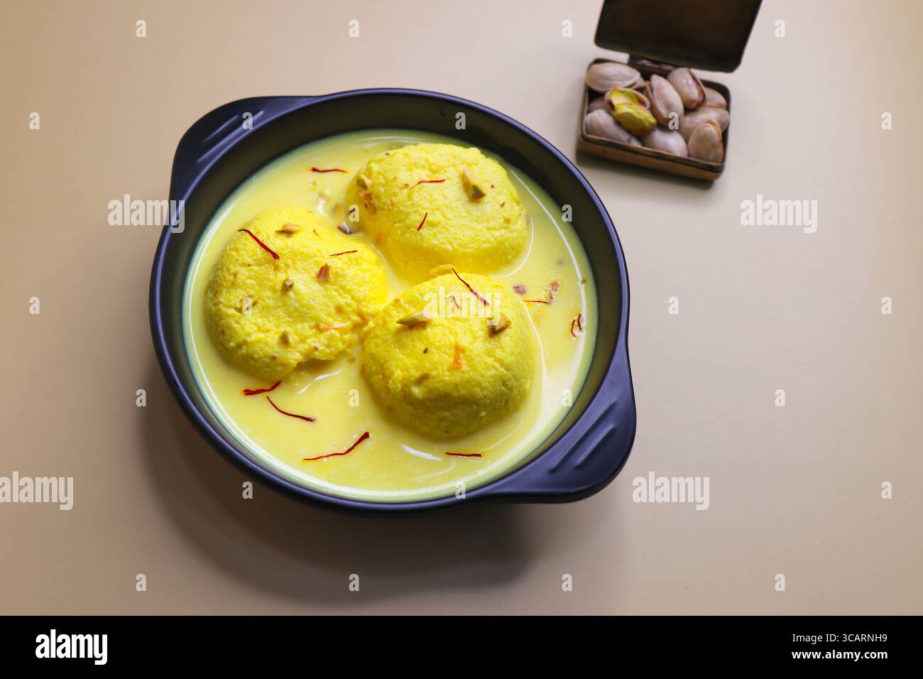 Rasmalai ist ein weiches, schwammiges Dessert aus Chenna oder Paneer. Eingeweicht in safrancremiger Milch, garniert mit gehackten Pistazien und Mandeln. Stockfoto