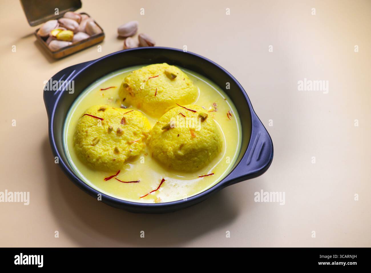Rasmalai ist ein weiches, schwammiges Dessert aus Chenna oder Paneer. Eingeweicht in safrancremiger Milch, garniert mit gehackten Pistazien und Mandeln. Stockfoto