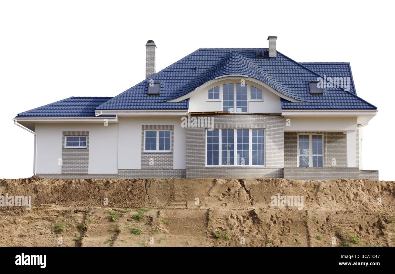 Neues Dream-Massenproduktionshaus mit blauem Schieferdach auf einem sandigen Hügel. Isoliert mit Patch Stockfoto