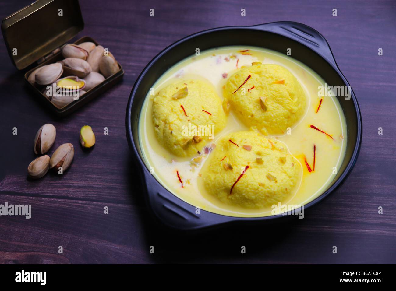 Rasmalai ist ein weiches, schwammiges Dessert aus Chenna oder Paneer. Eingeweicht in safrancremiger Milch, garniert mit gehackten Pistazien und Mandeln. Stockfoto