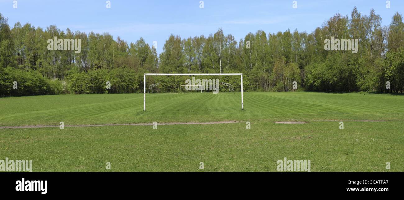 Panorama des frisch geschnittenen Frühlingsfußballrasens mit Eingangstor des ländlichen Clubs. Sonnige ländliche Landschaft am Frühlingstag Stockfoto