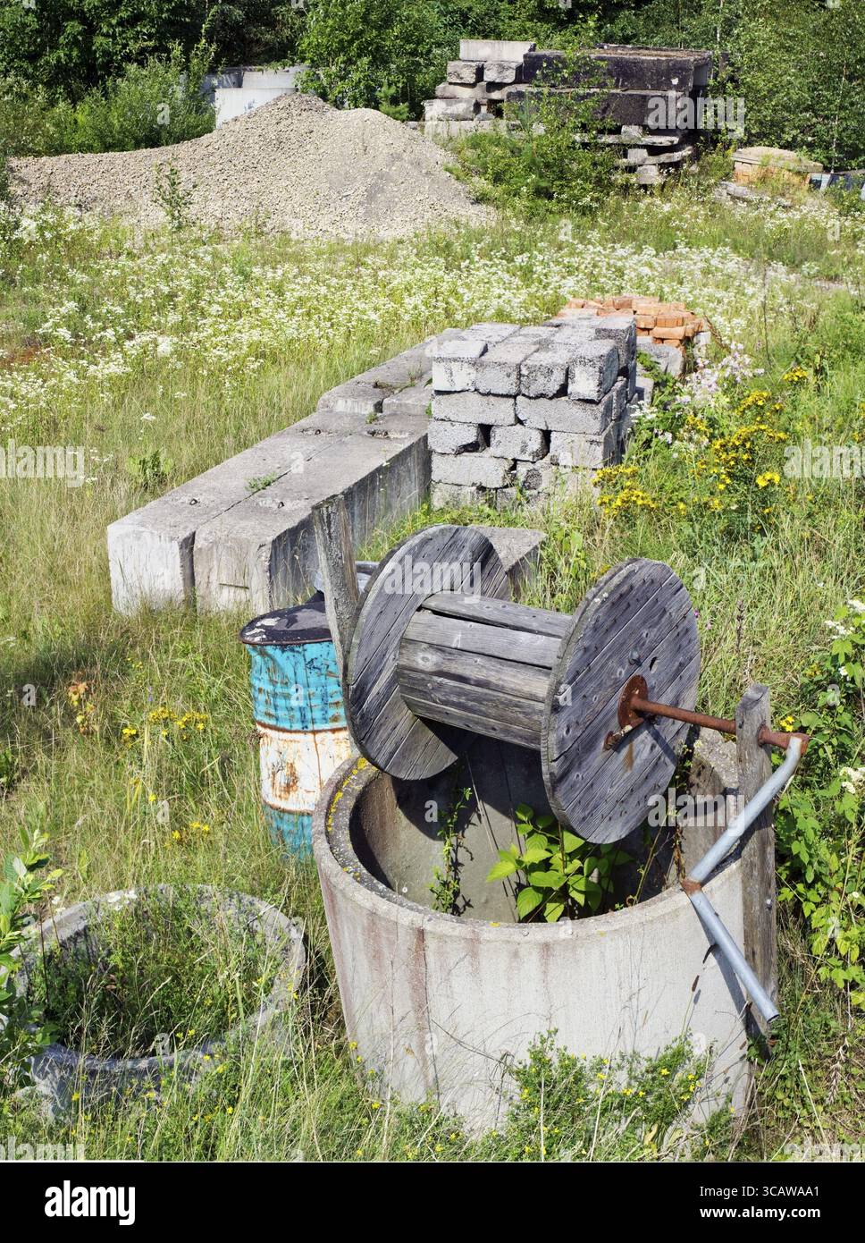 Das geworfene Gebäude des Landhauses im Sommerwald. Betonsteine, Ziegelsteine, Kies und Füllziegel sind auf einer grünen Lichtschicht verstreut. Panoram Stockfoto