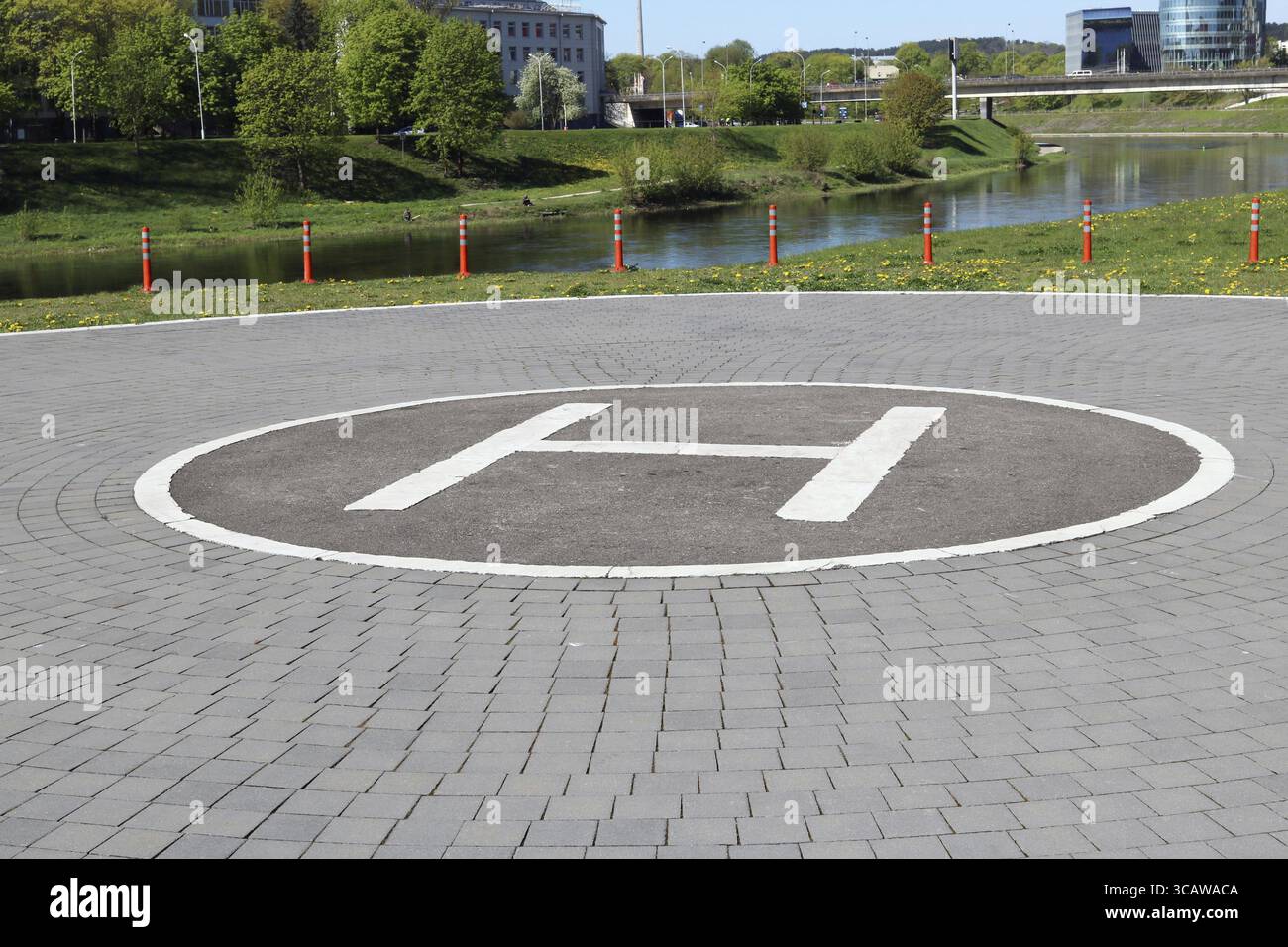 Die städtische Stadtplattform für Hubschrauber des Rettungsdienstes ist am Ufer des Flusses ausgerüstet. Frühling sonniger Tag Landskapazitäten Stockfoto