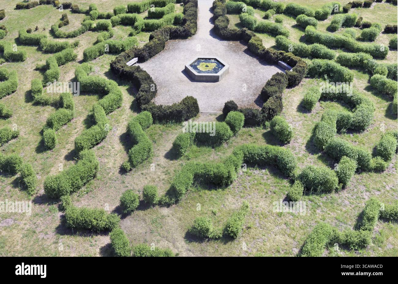 Die primitiven ländlichen Labyrinth im öffentlichen Park besteht aus geschnittenen niedrigen Büschen. In der Mitte der Komposition ist ein zerstörter Brunnen von einem sechseckigen Stockfoto