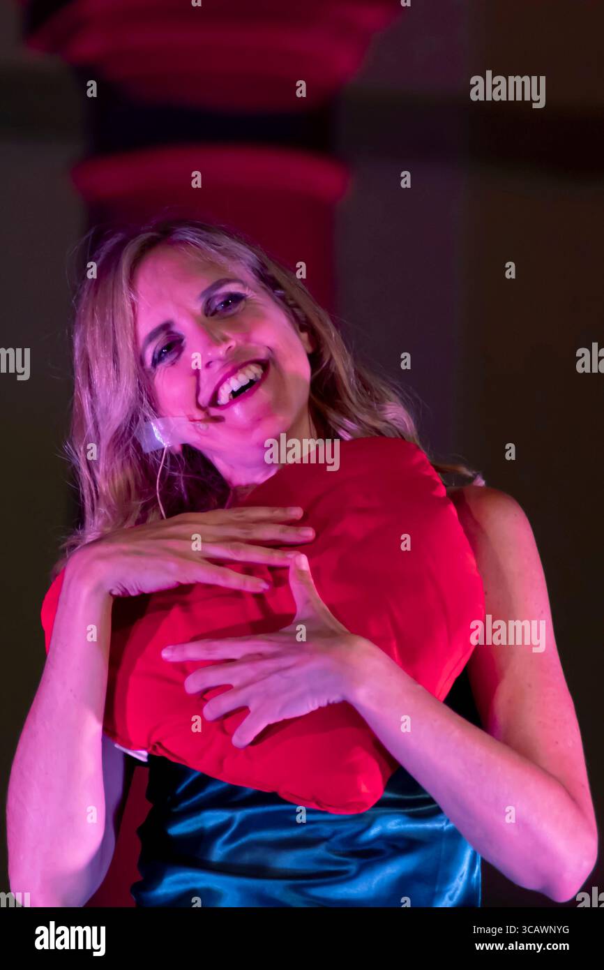 Die italienische Komikerin Ippolita Baldini umarmt während einer Vorstellung ein rotes Herzkissen Stockfoto