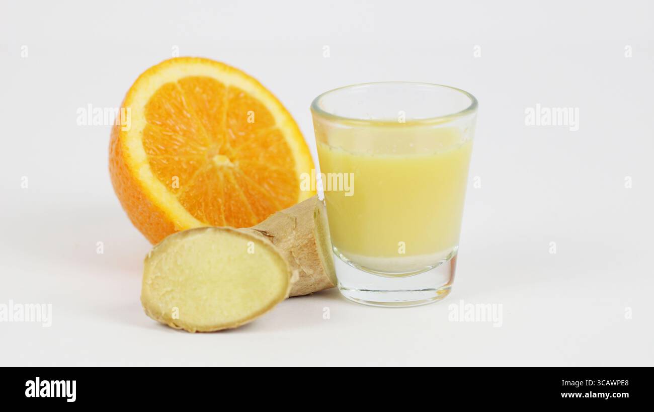 Frischer Ingwer in einem Glas, umgeben von geschnittener Ingwerwurzel und einer halben Orange auf weißem Hintergrund. Immunitätsverstärker und entzündungshemmendes Getränk. Stockfoto Frischer Ingwer in einem Glas, umgeben von geschnittener Ingwerwurzel und einer halben Orange auf weißem Hintergrund. Immunitätsverstärker und entzündungshemmendes Getränk. Stockfoto